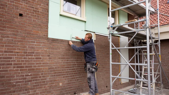 Vakman brengt gevelisolatie aan op een bakstenen woning